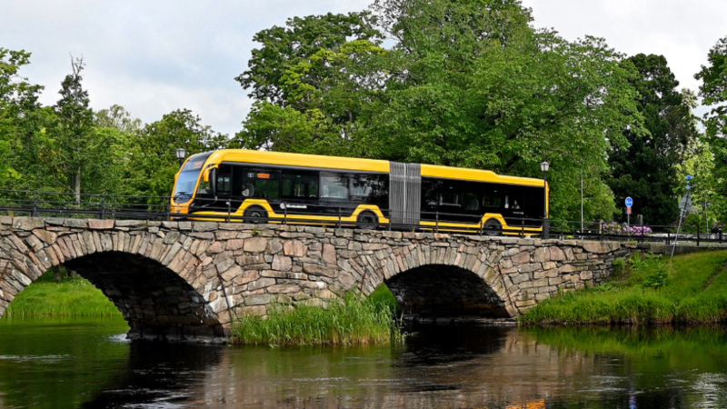 En gul S-linjebuss kör över stenbron i Karlstad
