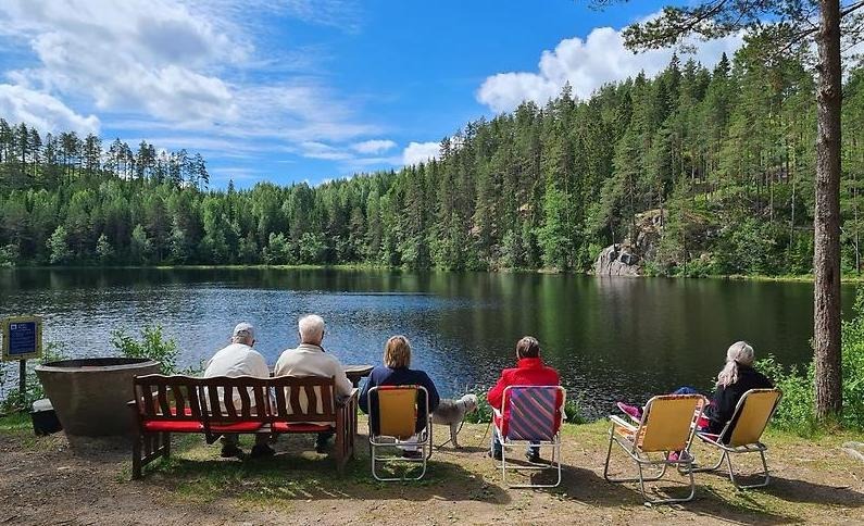 Pensionärer sitter vid en sjö och dricker kaffe