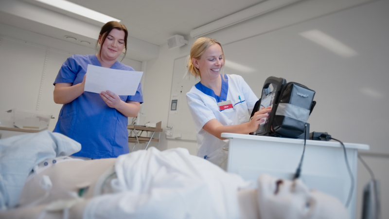 två läkare tränar defibrillering på en docka i ett patientrum