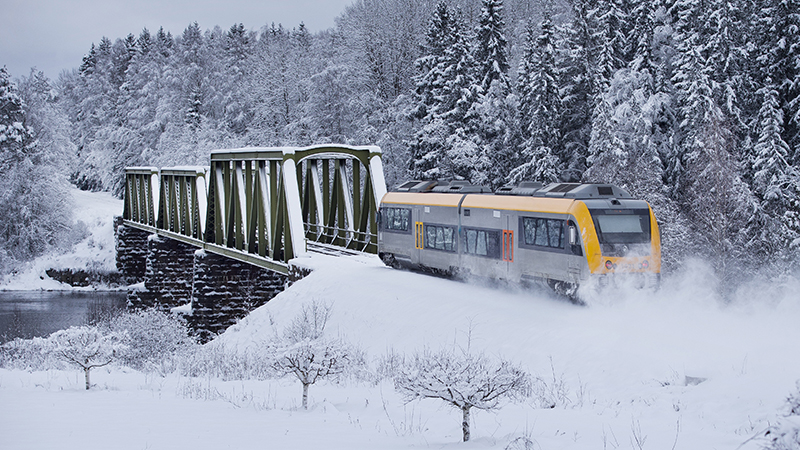 Tåg som åker på Frykdalsbanan, bilden är tagen under vintern och det är snö i bakgrunden