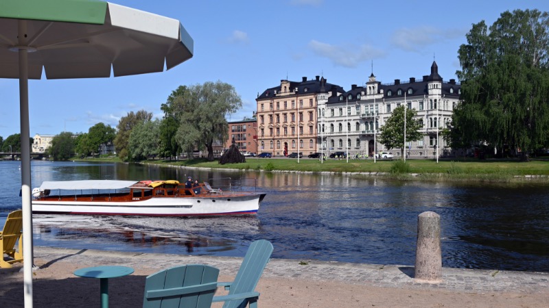 Båtbuss på älven i Karlstad med solstor och parasoll i förgrunden.