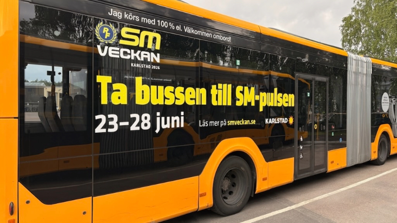 Foto på del av gul buss. På bussen finns en dekal där det står Ta bussen till SM-pulsen