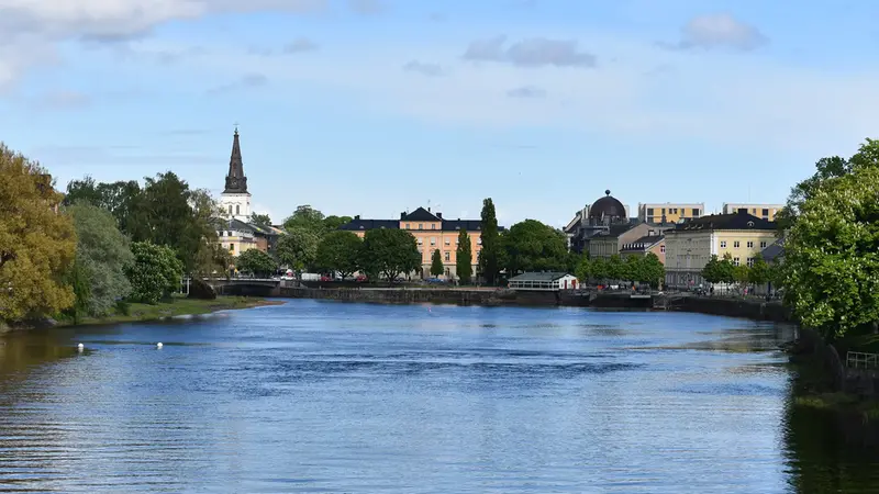 En älv med bro, kyrka och andra byggnade i bakgrunden.